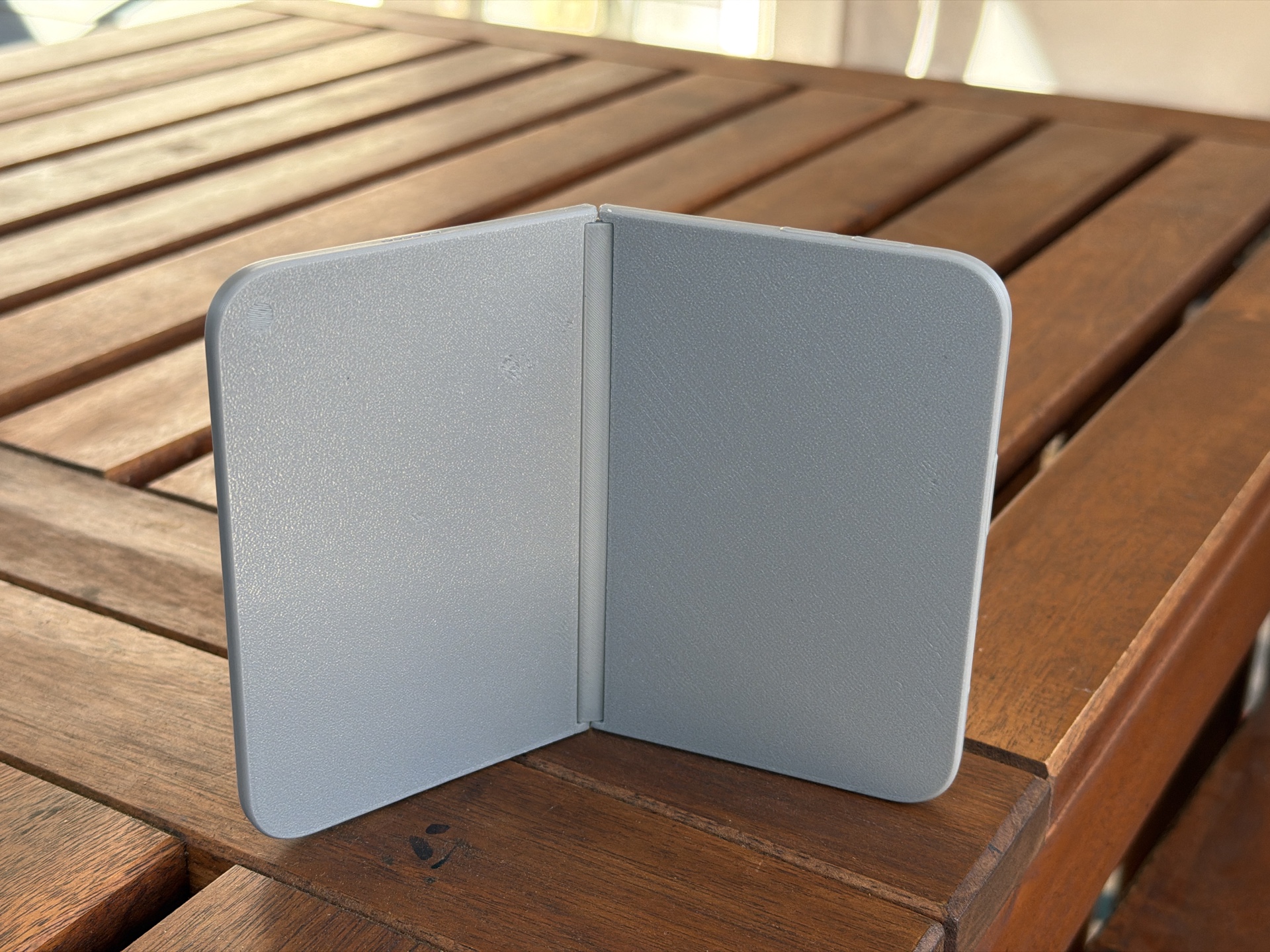 GPT Image 2.5 renders an app on a fake iPhone Duo in open-book pose (image 1 of 2)